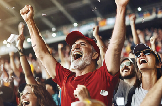 Image of a man standing in a stadium cheering along with people around him