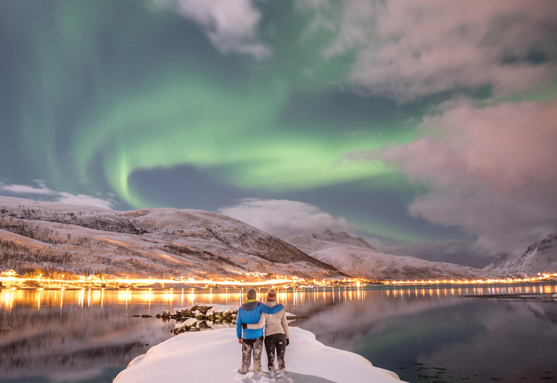 Photo of a couple looking out at the Northern Lights in Norway