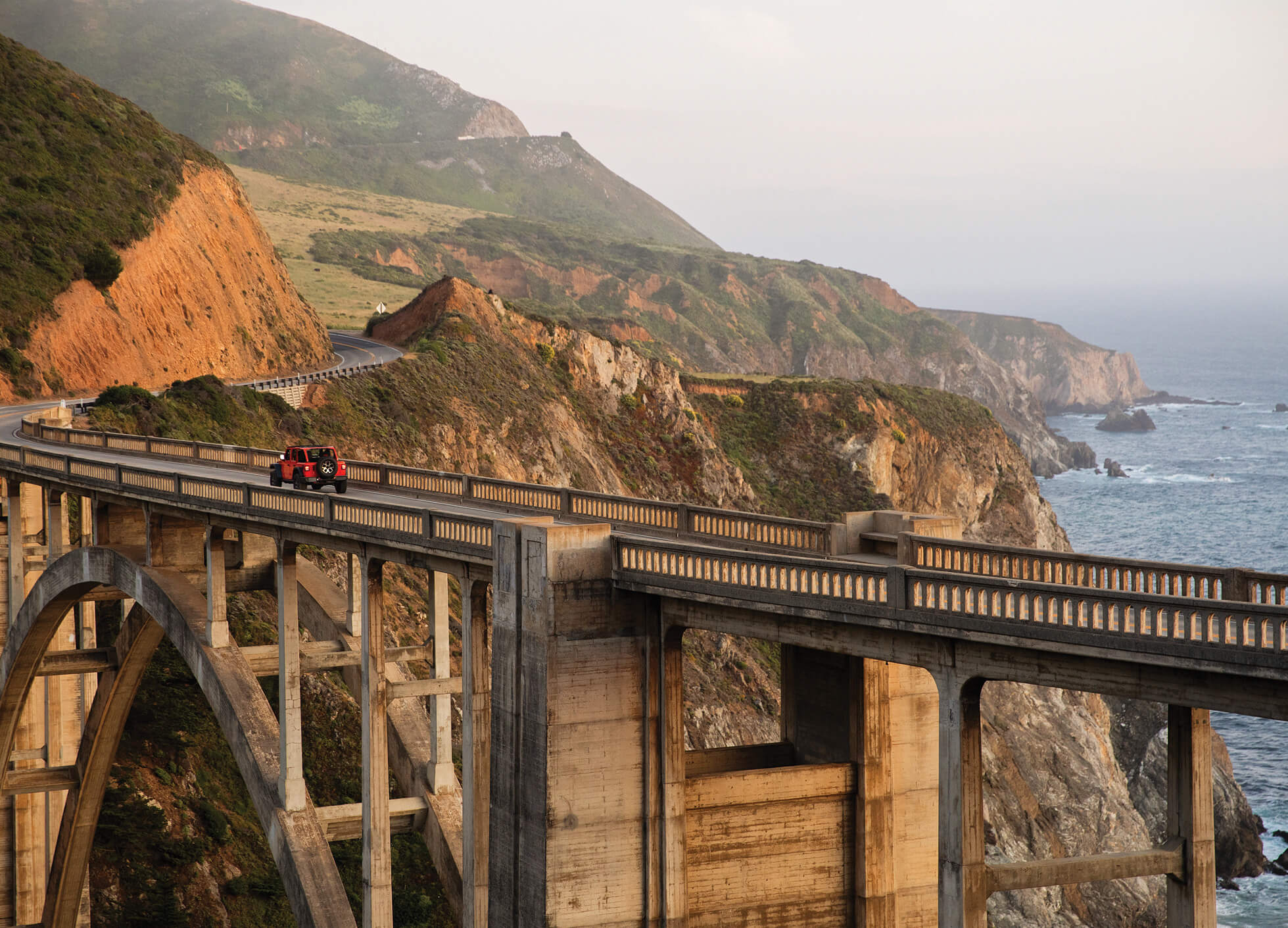 Photo of a car crossing a coastal bridge in Big Sur, California