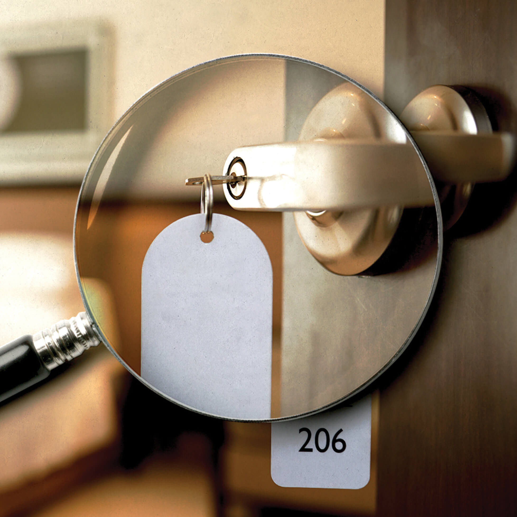 Photo illustration of a magnifying glass over a key in a hotel doorknob