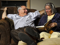 A couple enjoys the pleasure of reading out loud on the couch.
