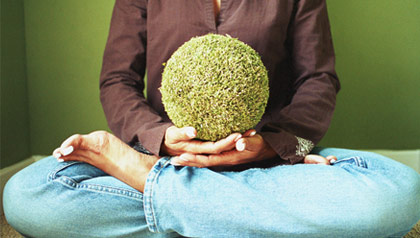 A woman holding a giant seed while meditating.