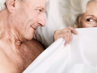 Better sex in the new year- a senior couple flirt in bed