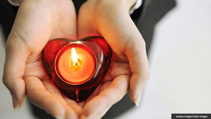hands holding candle in heart-shaped candle holder