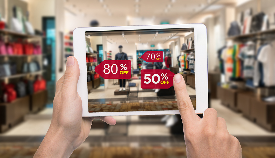 Hand holding digital tablet smart phone use AR application to check special sale price in retail fashion shop mall