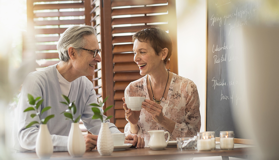 An older man and woman talking while drinking coffee