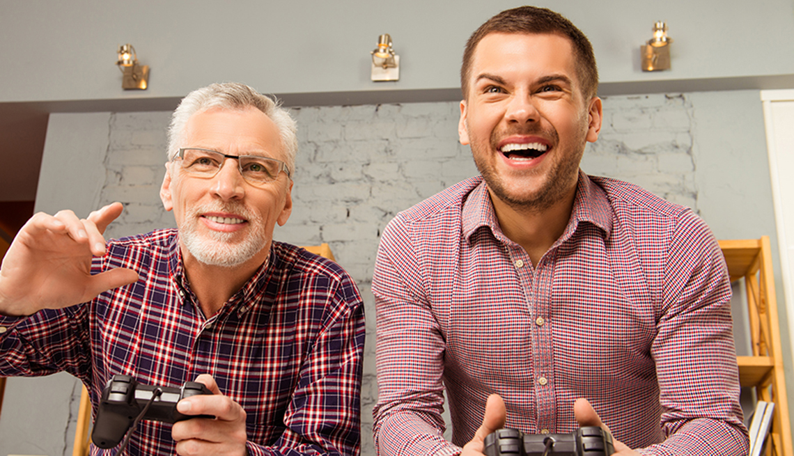 Older man and younger man playing a video game together at home