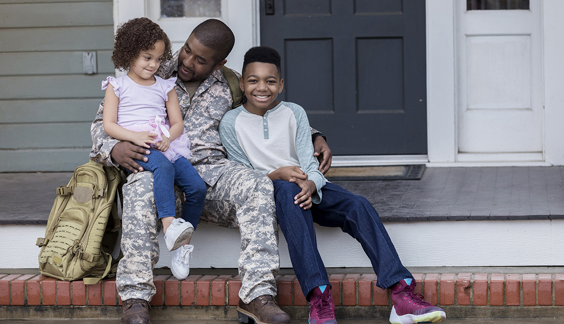 Army dad sits on the porch with his young son and daughter
