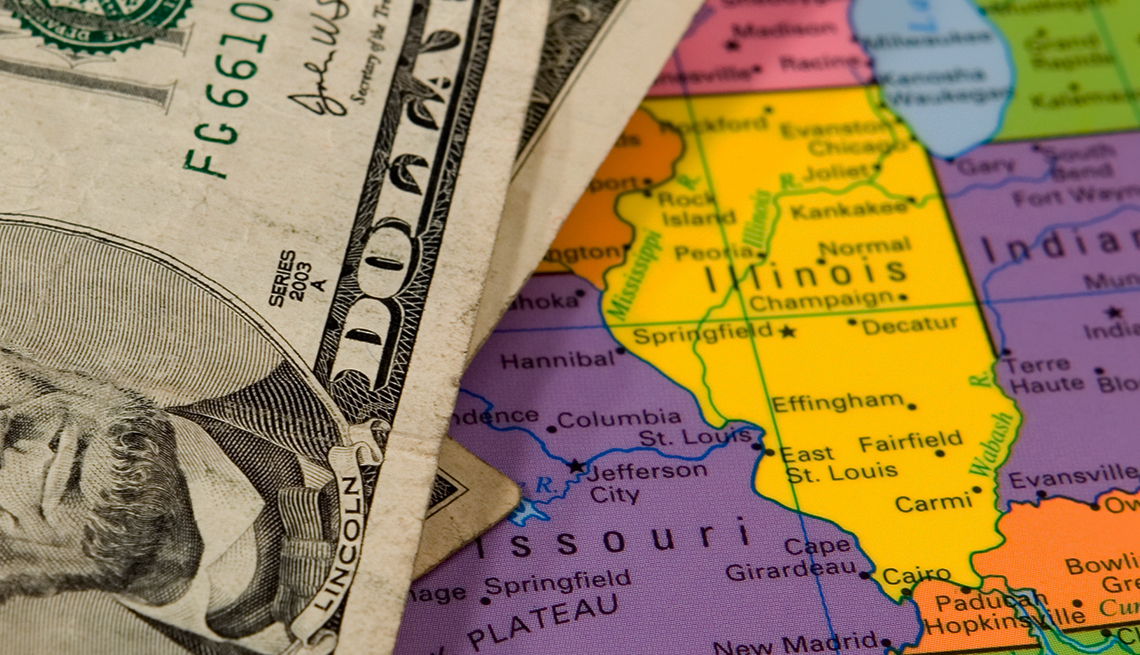 Five dollar bill on top of a colorful united states map