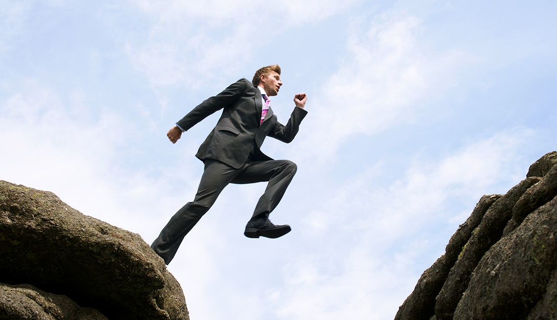 Man in suit leaps over crevice