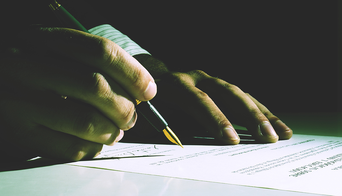 Person signing papers with dark background