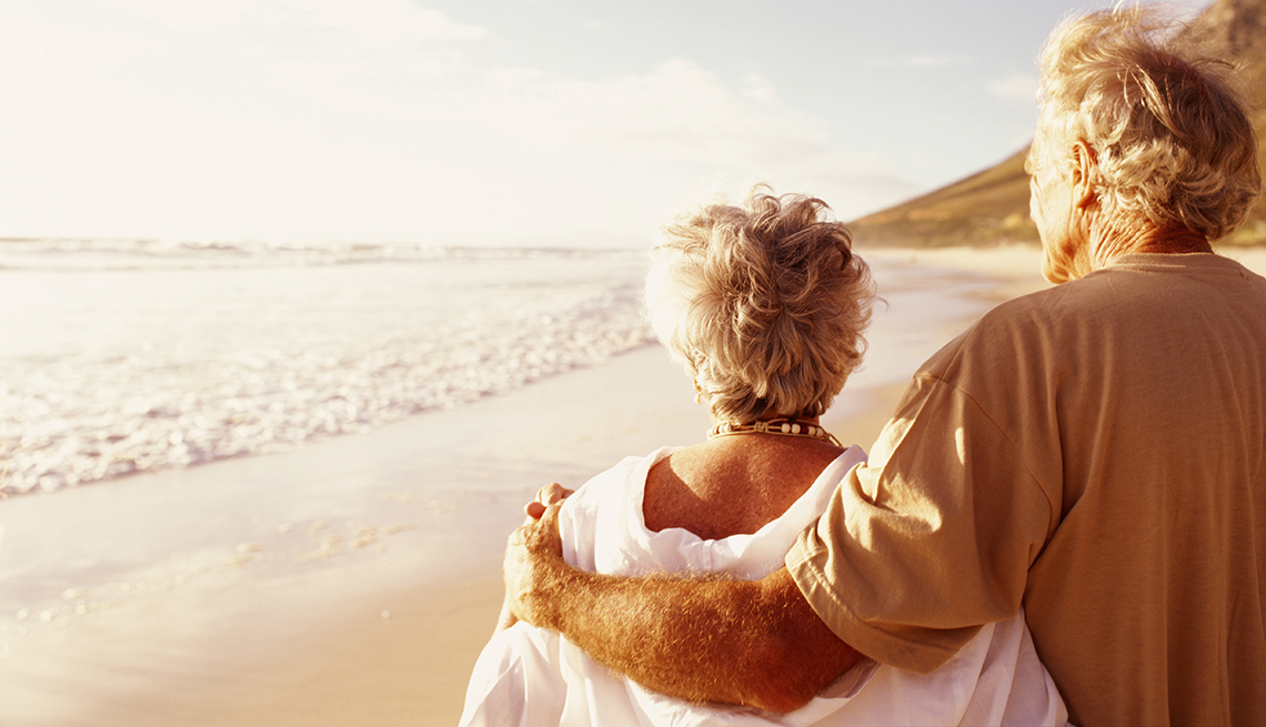 mature retired couple walking on the beach during sunset