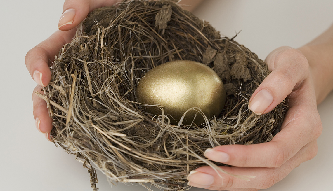 Manos sosteniendo un nido con un huevo de oro