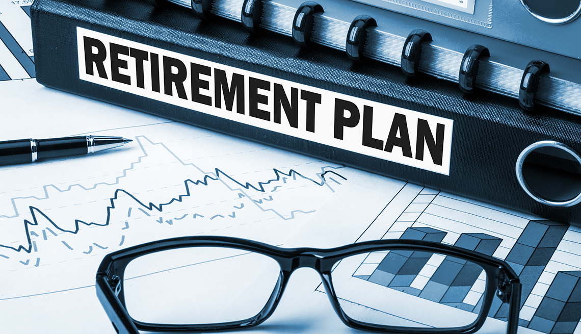 a binder spine label says retirement plan - it sits on graphs and glasses on desk