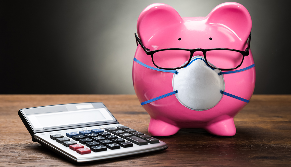Alcancía de color rosado con gafas y tapabocas al lado de una calculadora.