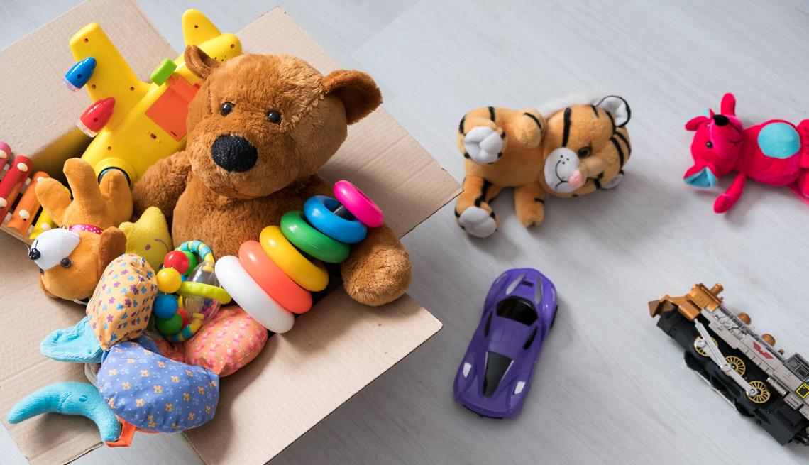 a box of toys on the floor including a teddy bear a toy tiger a car and a train