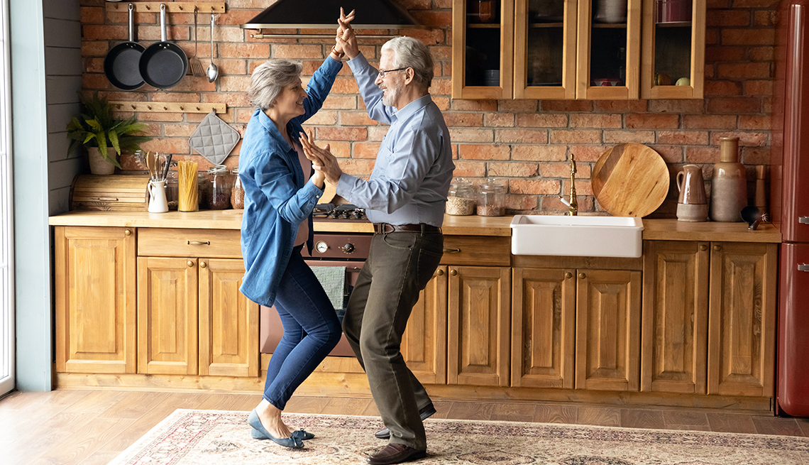 Happy retiree couple dancing in kitchen 