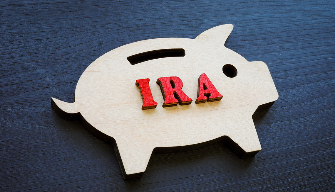 A flat wooden piggy bank on a dark background is labeled IRA.