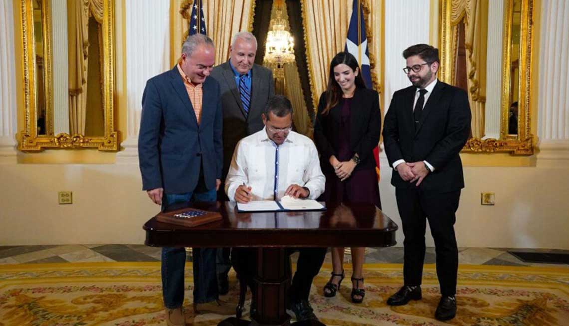 Al centro, el gobernador Pedro Pierluisi, junto a miembros de su gabinete y el director estatal de AARP Puerto Rico, José Acarón (detrás), durante la firma de la Ley 42. 
