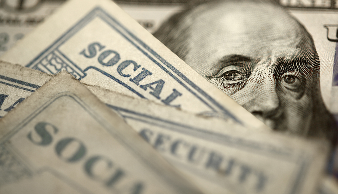 Ben Franklin's face on 5 dollar bill behind social security cards