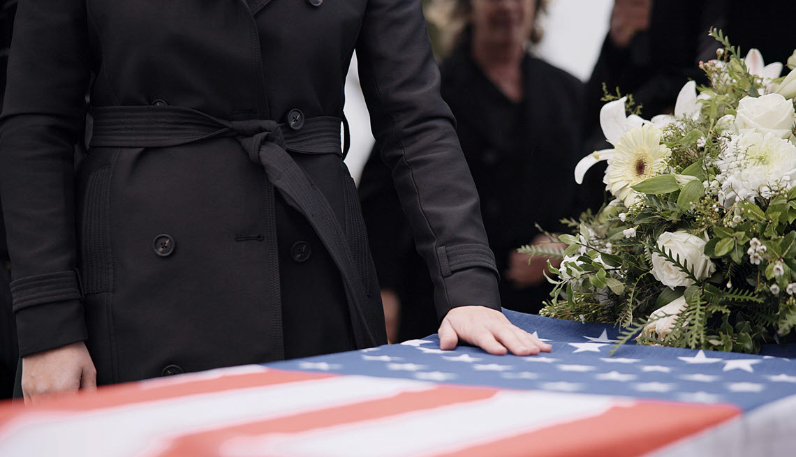 Man with hand on coffin at veteran funeral