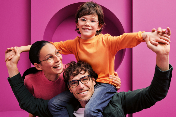 Family wearing glasses smiling with purple shapes in the background