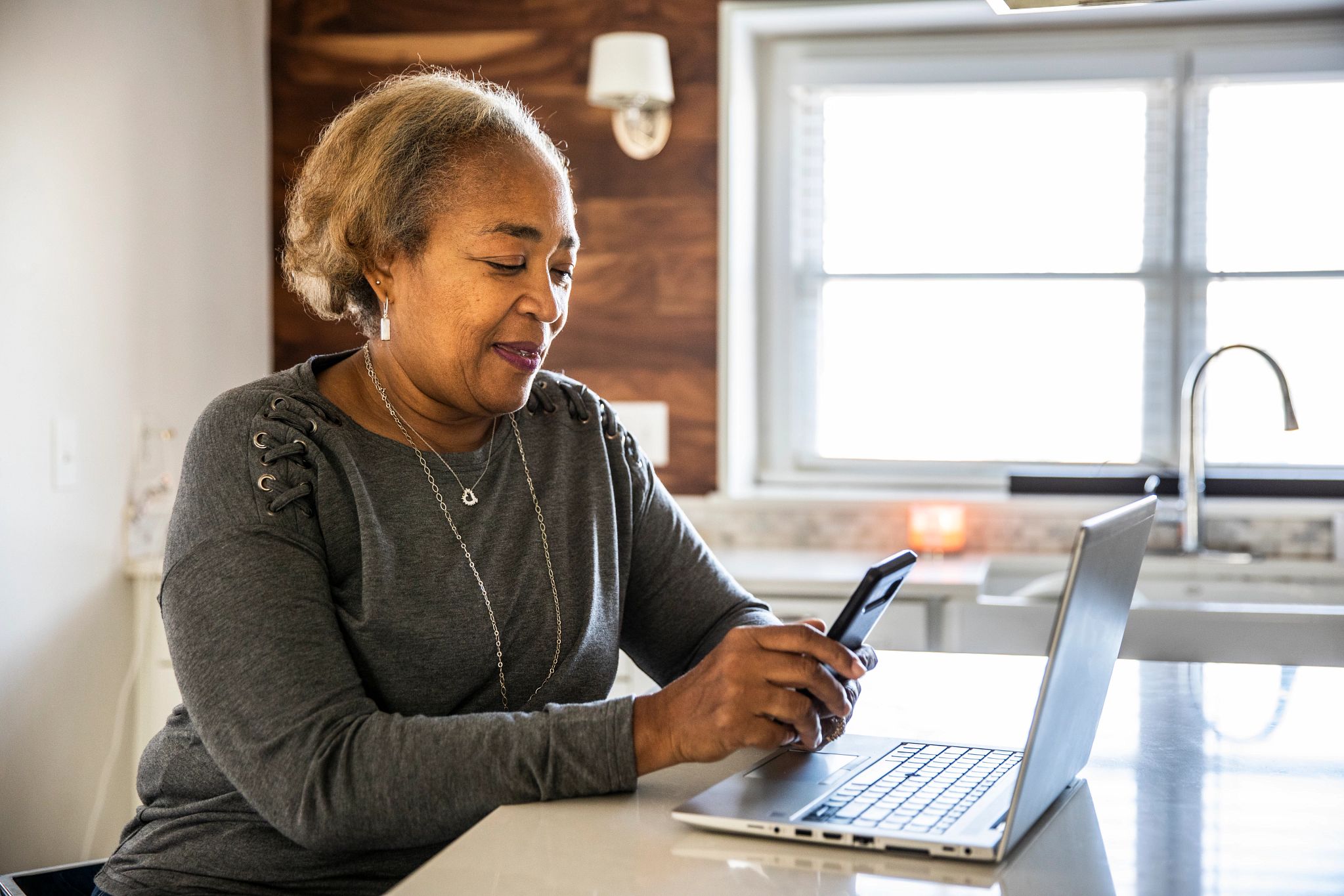 woman on cellphone with laptop on counter in front of her