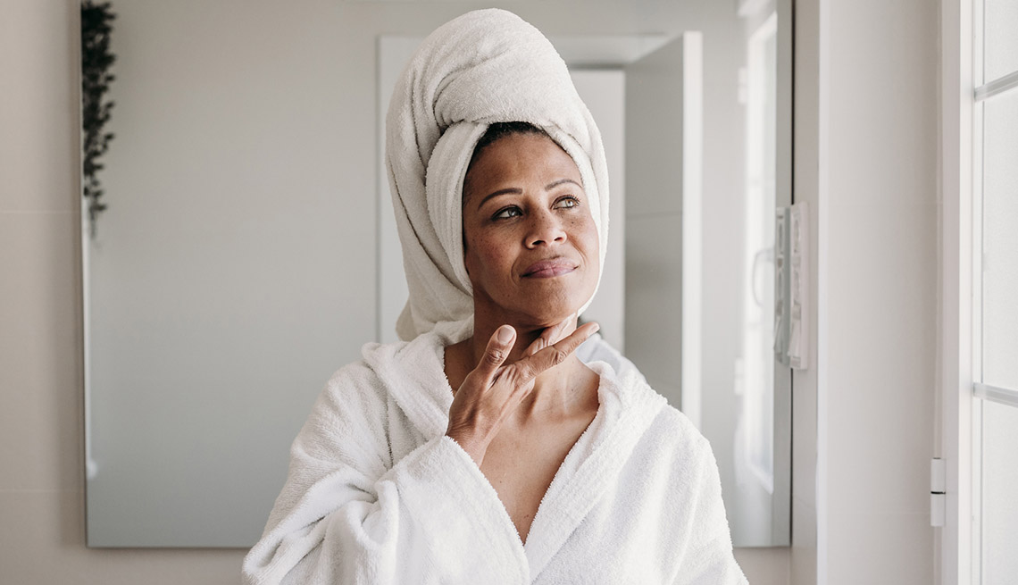 Woman applying moisturizer on face in bathroom