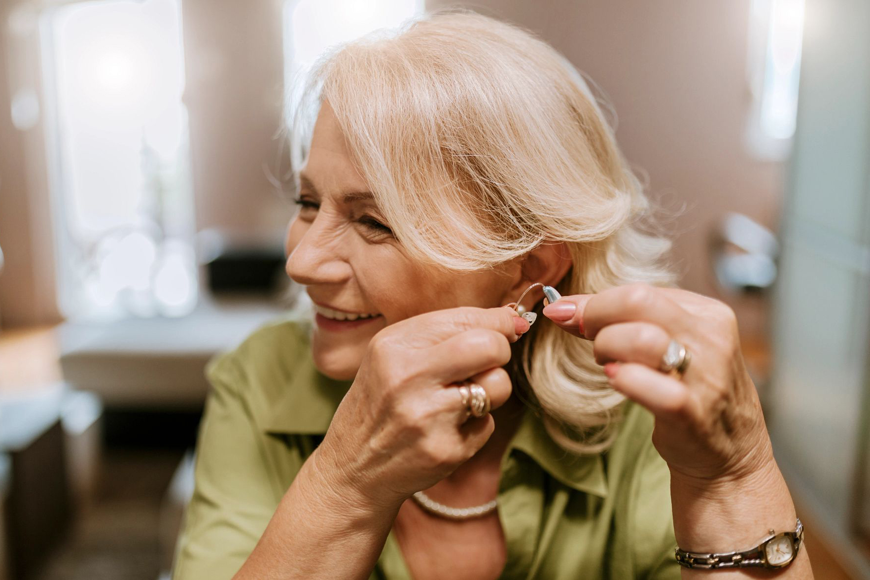 woman puts hearing aid in ear