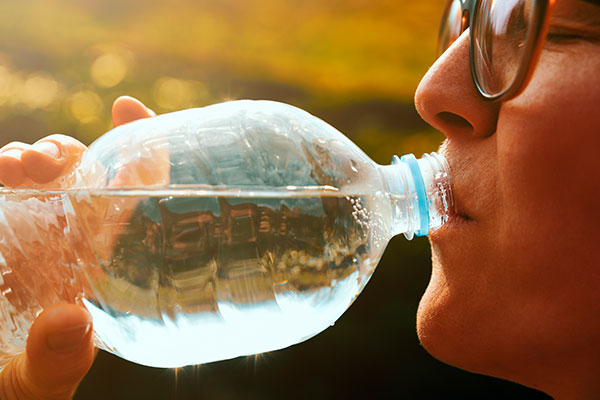 woman drinking from plastic water bottle
