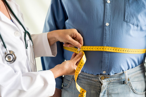 Doctor measuring a person's waistline.