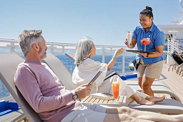 Couple receiving beverages on a sunny deck of a cruise ship.