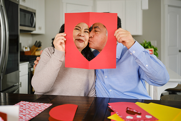 Couple kissing behind a homemade Valentine’s Day card.