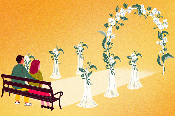 Couple sitting at the start of a wedding aisle.