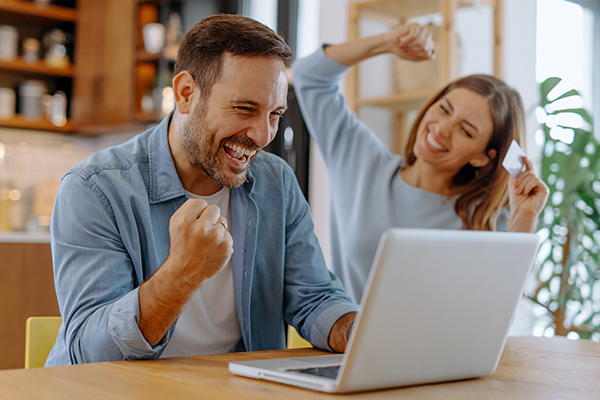 Excited couple using a laptop.