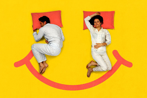 Couple lying down on a large smiley face.