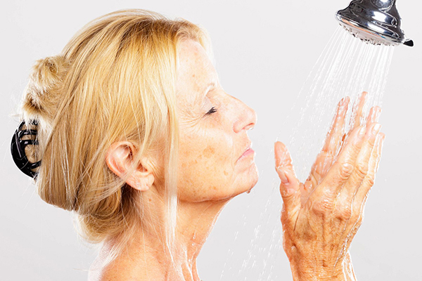 Person holding their hands under a showerhead.