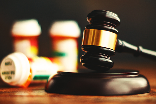 Gavel resting next to prescription bottles.