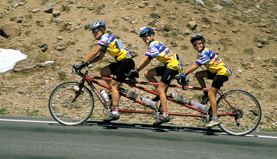 Tres personas montan una bicicleta en las montañas