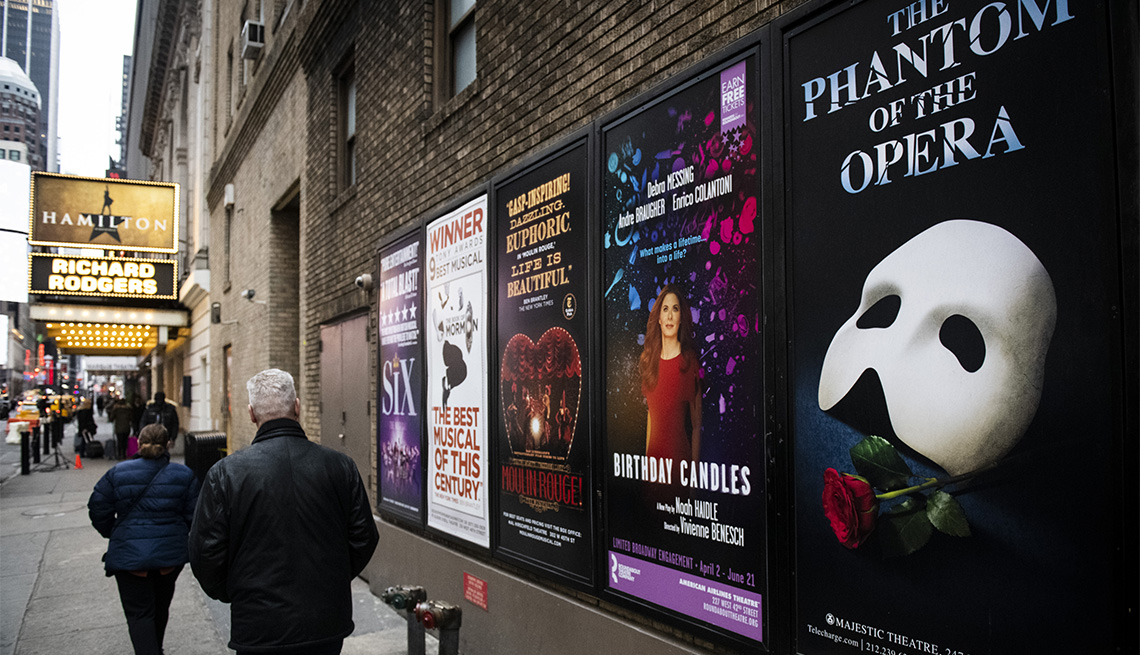 Pedestrians walk past Broadway posters in the Times Square neighborhood of New York among the coronavirus pandemic