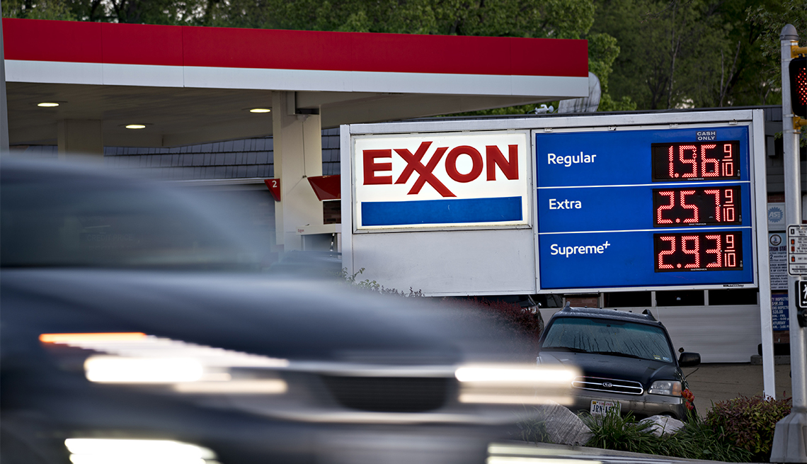 Un vehículo pasa por una estación de servicio Exxon Mobil que muestra los precios de la gasolina