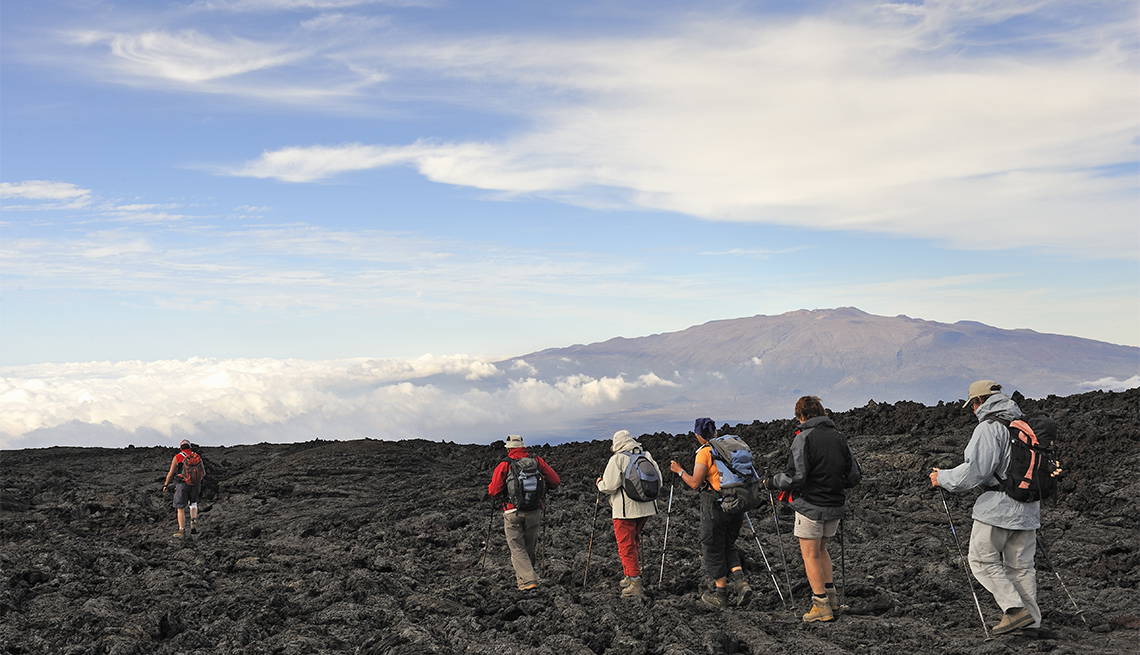 Group of hickers walking on cooled lava, Mauna Loa Volcano (Mauna Kea in the background), Big Island, Hawaii Islands