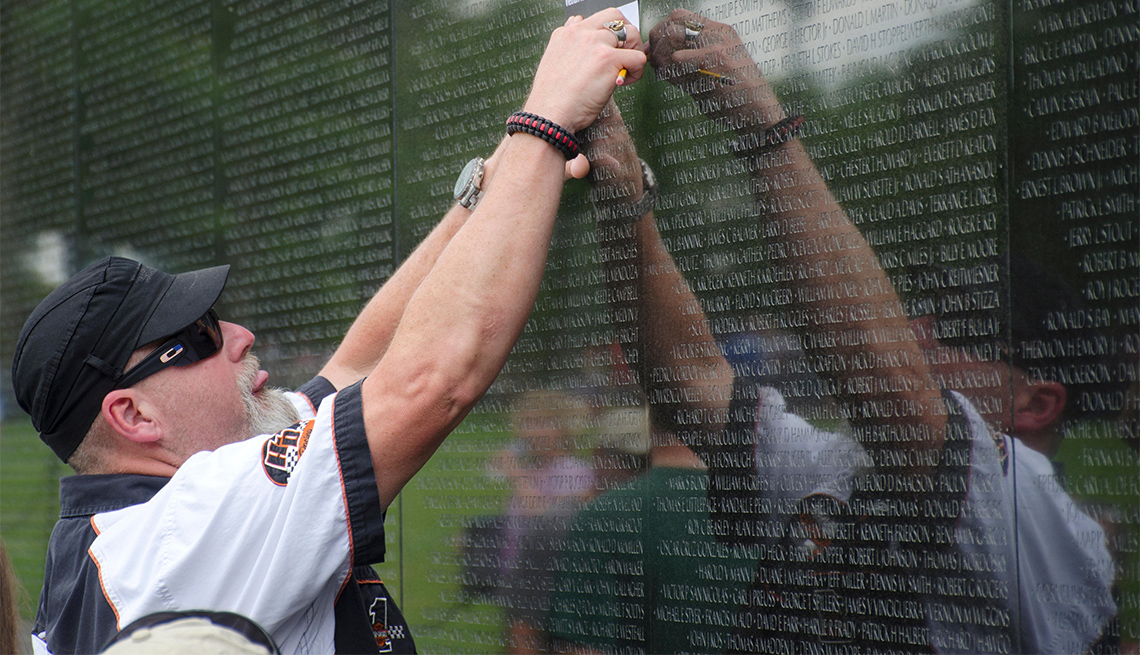 Hombre lee los nombres de soldados caídos en el muro negro del Monumento a los Veteranos de Vietnam
