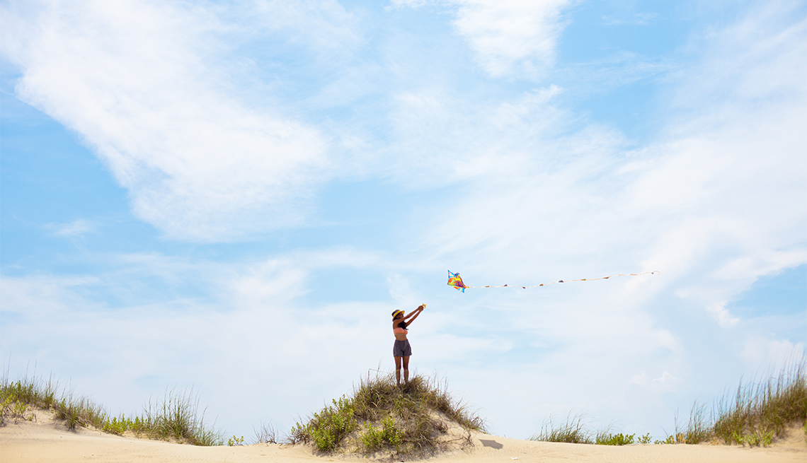 item 3 of Gallery image - A woman flying a kite on a beach in the Outer Banks