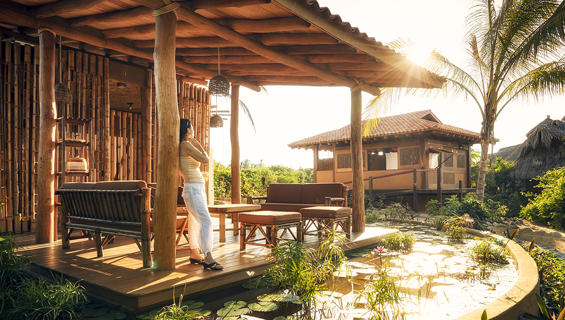 item 11 of Gallery image - Mujer parada en el porche de un bungalow ecológico en el resort Playa Viva