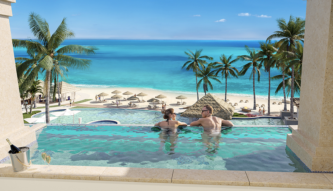 Dos adultos descansan en una piscina con vista al mar caribe