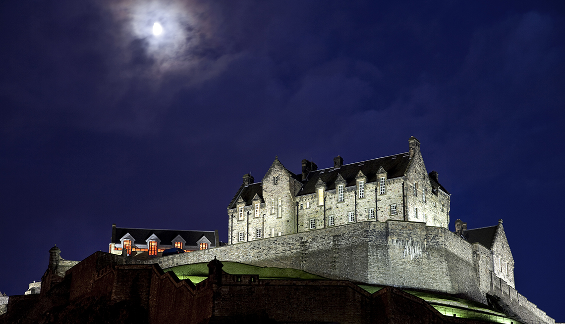 Luna en las nubes sobre Spotlit Castillo de Edimburgo en la noche