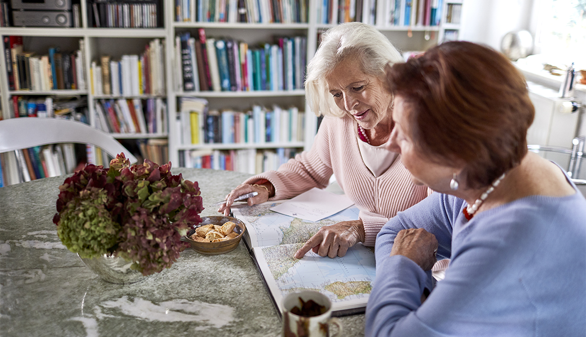 two women sitting at a table looking at a map, planning a trip