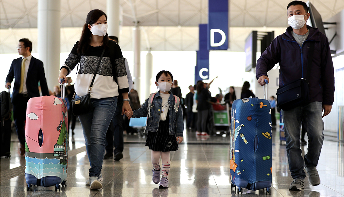 Travelers wearing face masks and pushing suitcases walk through the check-in hall at the Hong Kong International Airport in Hong Kong, China, on Wednesday, Jan. 22, 2020. China ramped up efforts to contain a new respiratory virus thats killed nine people 