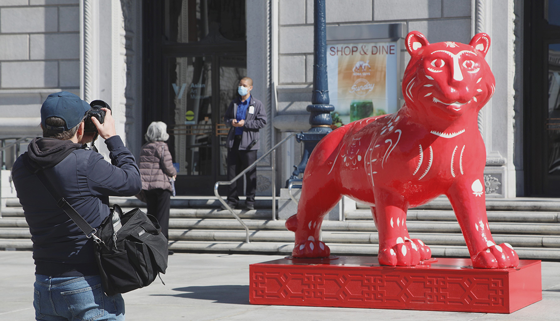 Persona toma fotos de una escultura con forma de tigre de color rojo